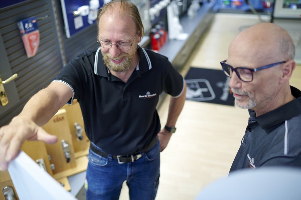 Zwei Männer diskutieren über einem Dokument in einem Geschäft mit Produktregalen im Hintergrund.
